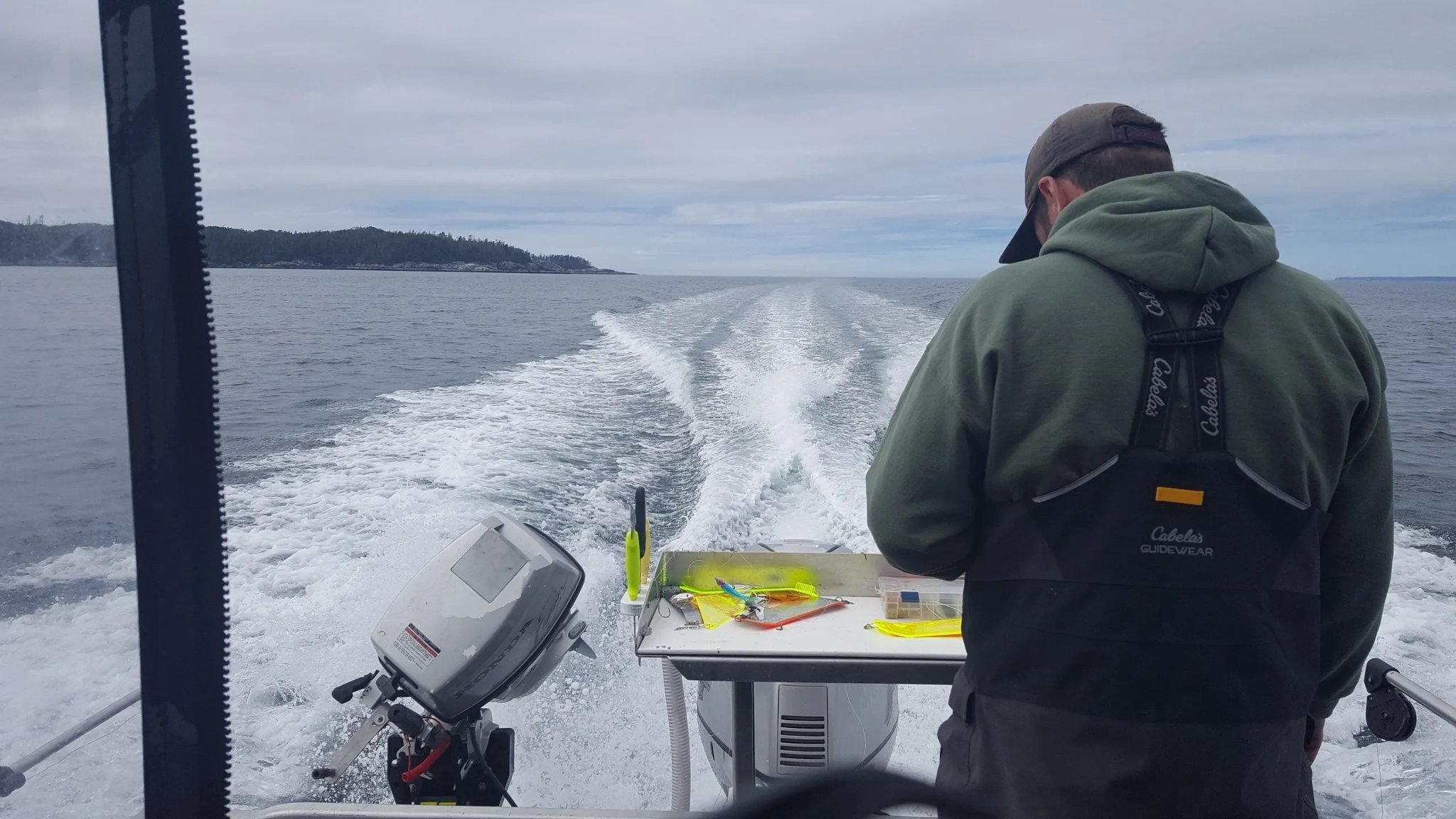 Angler rigging lures at the stern as the Tongass Troll leaves a white wake