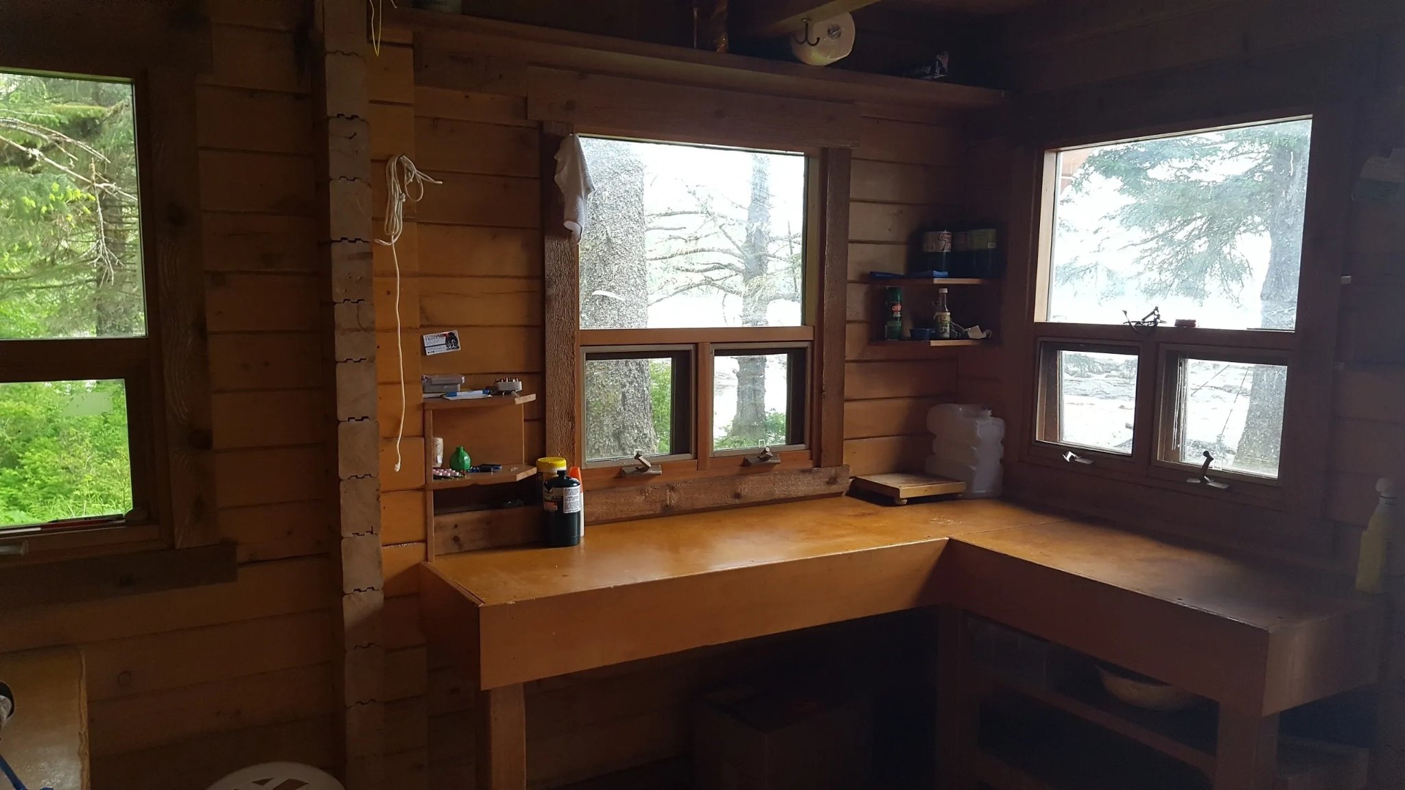 Interior of a remote Forest Service cabin with panoramic windows overlooking the rainforest