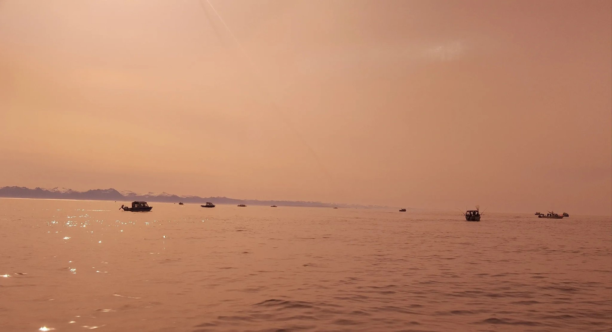 Fleet of fishing boats spread across a rose-gold sunset on Sitka Sound